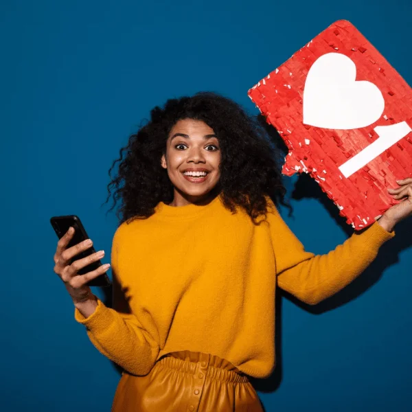 Young woman with a smartphone holding a "heart" symbol associated with social media usage
