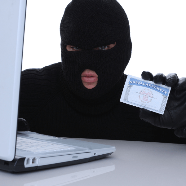 a thief posing with a SS card in front of a laptop, illustrating the concept of identity theft