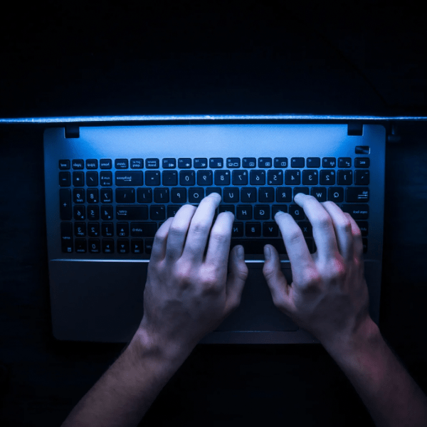 hands of a person typing on a laptop in darkness